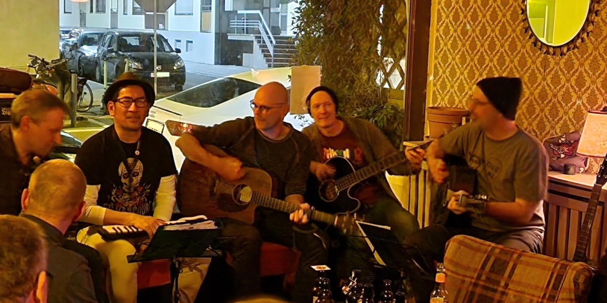 Die 5 Corduroys in Action in Wohnzimmerkulisse vor großer Scheibe, draussen ein Stück Sandweg mit Autos