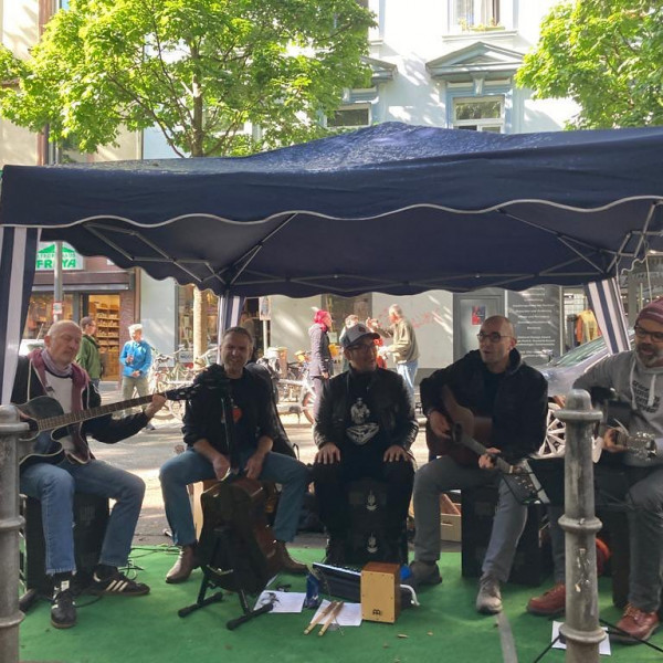 Die Jungs sitzen unter einem Pavilon und machen Musik