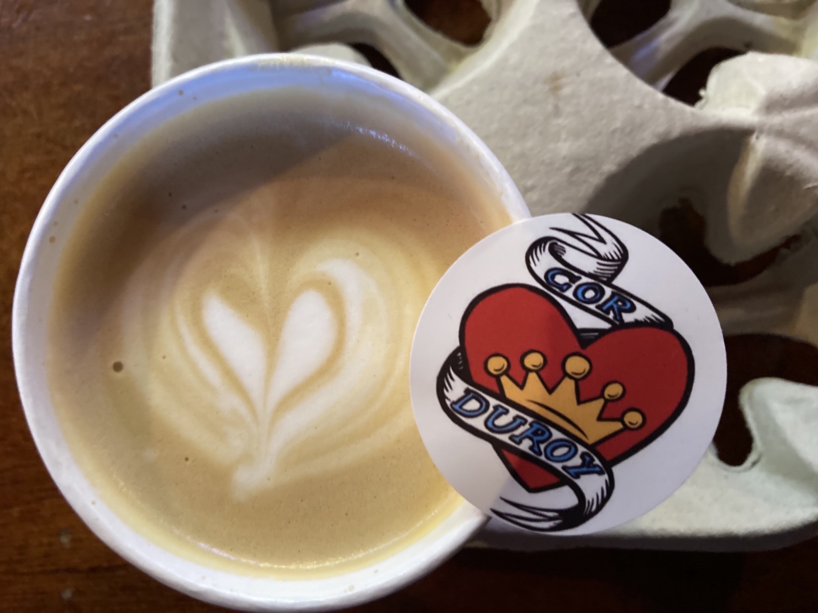 Corduroy Logo Sticker mit Herz neben einem Cappucino mit Herz im Schaum